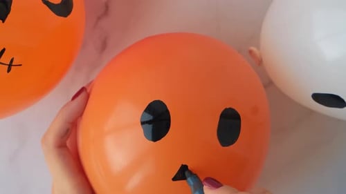 Woman Decorating Halloween Balloon with Marker