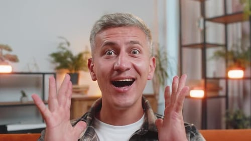 Man Expressing Joy and Surprise While Sitting on Couch