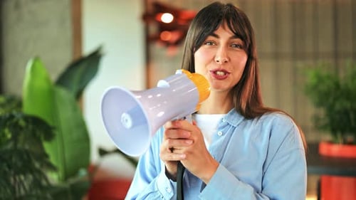 Cheerful Woman Making Public Announcement with Megaphone in Modern Office