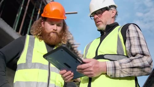 Intelligenter Ingenieur und Bauarbeiter, moderne Kollegen, die das Bauwerk mit einem Tablet inspizieren