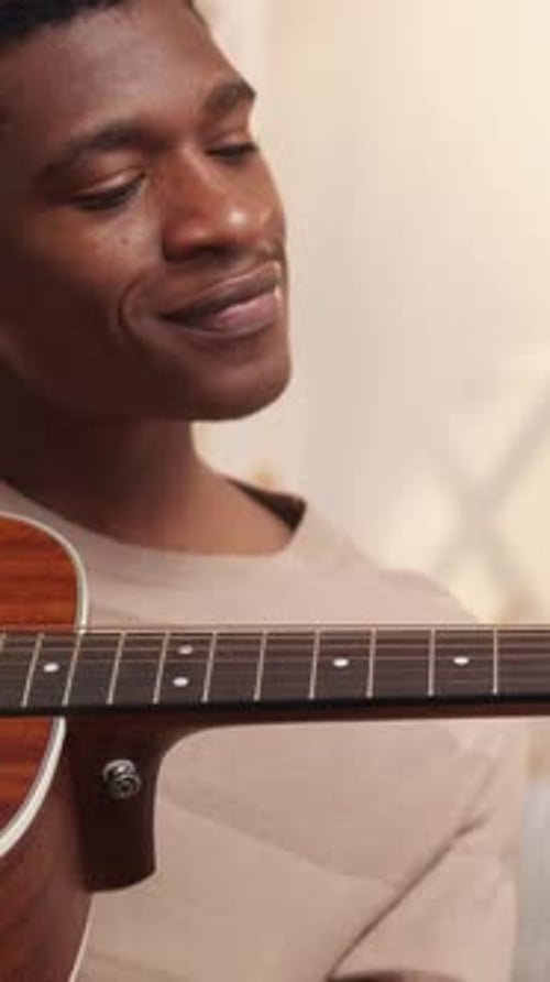 Young Adult Plays Guitar Indoors at Home