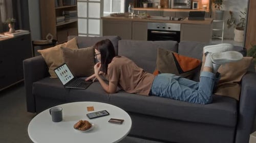 Woman Relaxing on Couch Shopping Online with Laptop