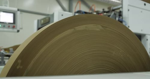 A Large Roll of Paper is Spinning on an Industrial Printing Machine a Production Process in a Modern