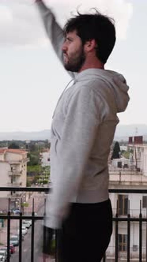 Man Stretching on Balcony in Urban Setting