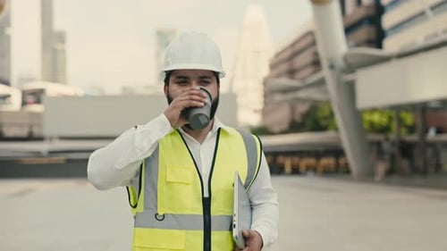 Portrait of Indian Engineer Holding Coffee and Laptop Walking Across City Square