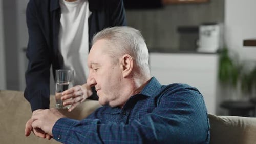 Elderly Man Taking Pills with a Glass of Water