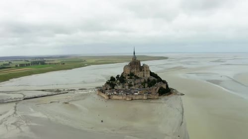 There is a castle in the middle of mont saint michel beach where there are many buildings castle in