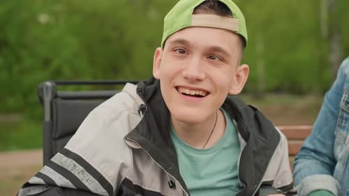 Smiling Young Man Waving and Making Peace Sign