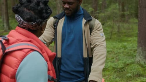 Woman sprays man with bug spray in forest