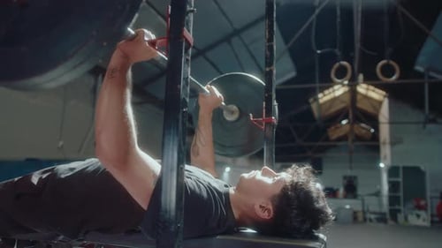 Young Man Doing Barbell Bench Press in the Gym