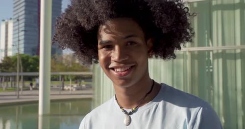 Young Handsome Black African American Man Looking at Camera Smiling in the Campus During a Sunny Day