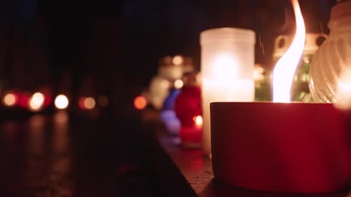 Grave Candles Lights Glowing on Cemetery at Night on All Saints Day