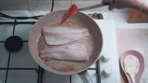 Woman pirien fish in a pan at home. close-up. homemade fish grill