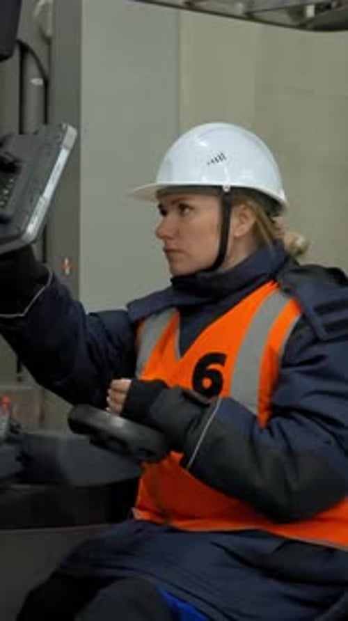 Vertical of Female Engineer Sits in Forklift Cabin Looking at Monitor