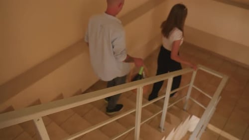 Man and Woman Walking Down Steps Inside