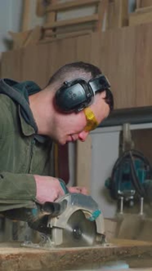 Carpenter Young Caucasian Man Works in Carpentry Shop Carpenter Saws Wooden Board with Circular Saw
