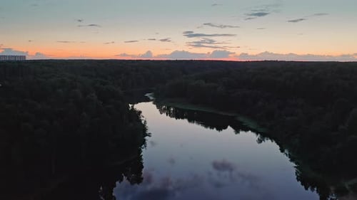 Flug über die Spiegelfläche des Flusses im dunklen Wald in der Abenddämmerung