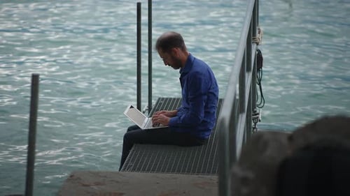 Man Working on Laptop by Rippling Blue Water