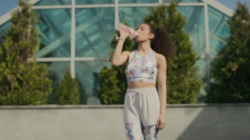 Woman Drinks Water Bottle During Workout Pause