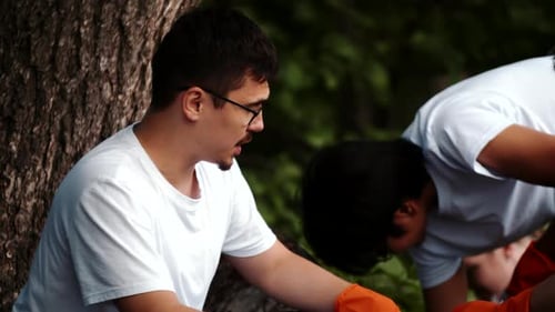 Portrait Closeup of a Young Guy Collecting Garbage in a Plastic Bag in Nature and Smiles Looking at