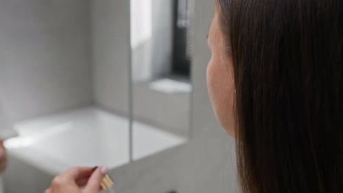 Woman Applies Face Serum in Bright Bathroom