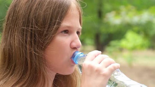 Close Up Preteen 11 Years Old Girl Drinking Clean Water From Bottle on Nature Background