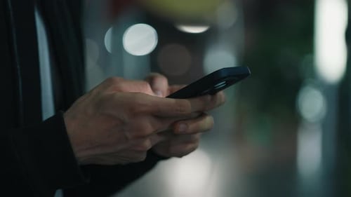 Adult Typing on Phone at Night in Urban Setting
