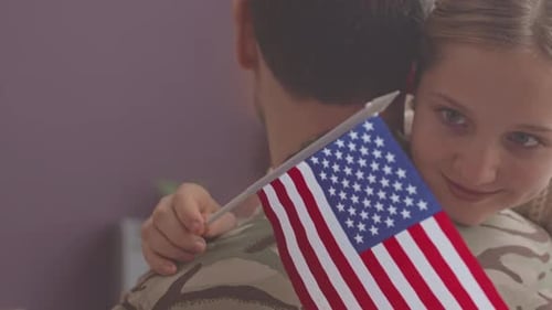Emotional Homecoming: Woman Hugs Soldier with US Flag