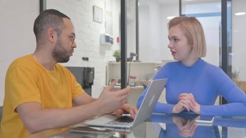 HIspanic Woman Discussing Work on Laptop with African Man
