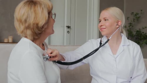 A Female Doctor Listens to a Patient's Heart with a Stethoscope