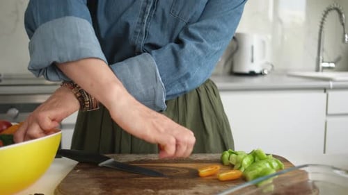 Woman cutting fresh colorful vegetables on wooden cutting board
