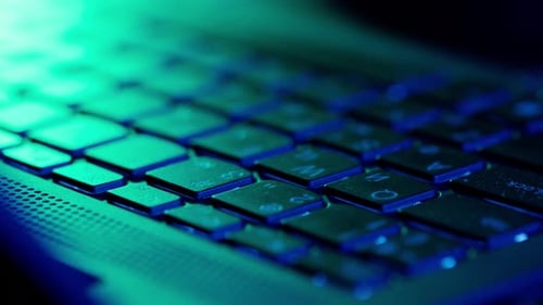 Closeup of Keyboard DJ Mixing Board in Neon Club Lights