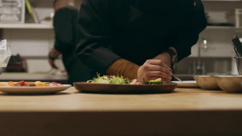 Professional chef adds finishing touches to exquisite salad in restaurant kitchen