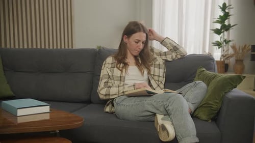 Woman Reading Book on Sofa in Living Room