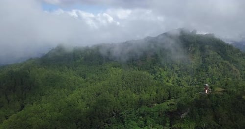 Forward drone video of rain forest and hill shrouded by thick fog. Very dense forest overgrown with