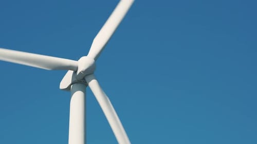 Large wind turbine in field against blue sky on sunny summer day slow motion