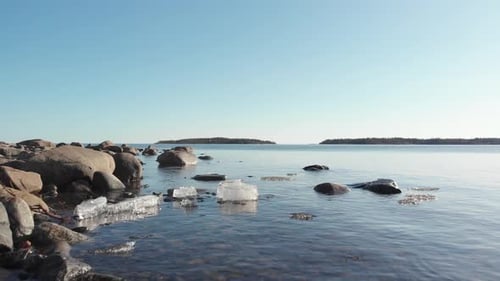 Low drone shoot of melting ice floating in cold water in north of Sweden. Sunny calm day.