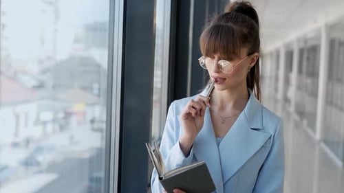 Young Woman Taking Notes in Office Hallway