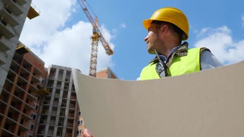 Construction Worker Holding Blueprint At Construction Site
