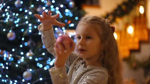 Little Girl with Christmas Ornament in Home
