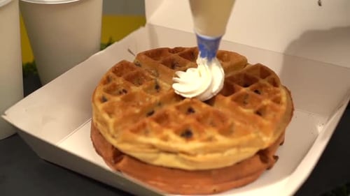 Waffeln mit süßer Schlagsahne belegen (Zeitlupe)