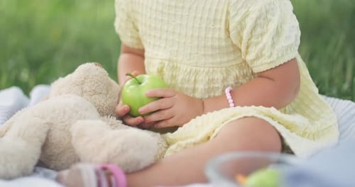 Abgeschnittene Ansicht Unerkennbares Kind Kleines kaukasisches Mädchen hält Apfel in Händen im Park im Sommer am