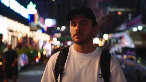 Young Male Tourist Walking Through a Busy City at Night