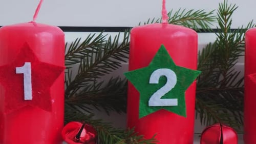 Vier rote Adventskerzen mit Zahlen, Tannenzweigen und weihnachtlicher Zero Waste-Dekoration auf der Fensterbank