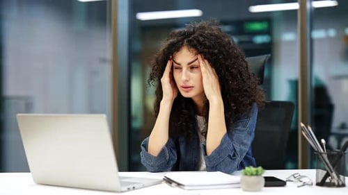 Stressed Young Woman Works at Computer in Office