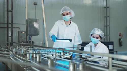 Deux superviseurs féminins inspectent le processus de production sur le convoyeur d'une usine alimentaire.