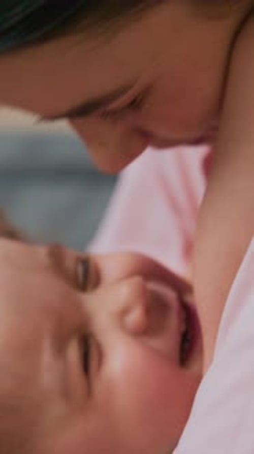 Loving Woman Holding and Feeding Baby Indoors