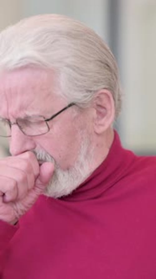 Senior Man Coughing into Hand Indoors Portrait