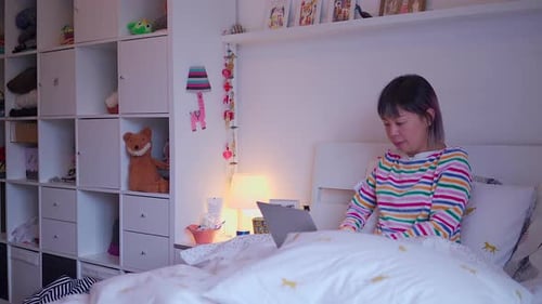 Woman Typing on Laptop Computer in Bed