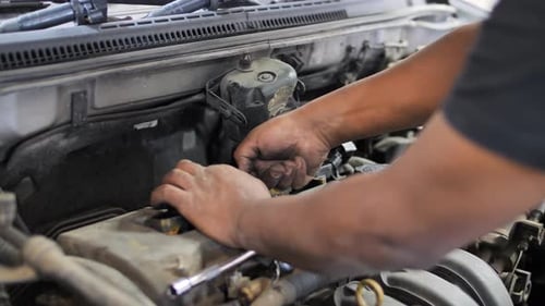 Hands of mechanic repairing engine inside open car hood, auto service